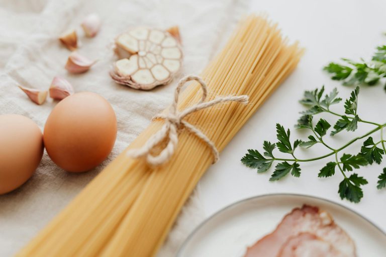 A flat lay of fresh ingredients including spaghetti, eggs, garlic, and parsley for a delicious pasta dish.